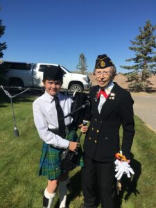Youth piper receiving a pin from Veteran Honor Guard leader.