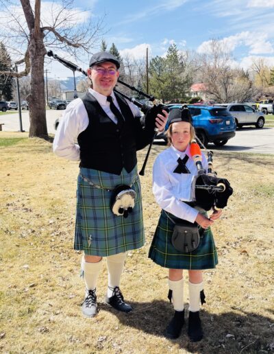 Adult & Youth Bagpipers standing on lawn after a veteran memorial.